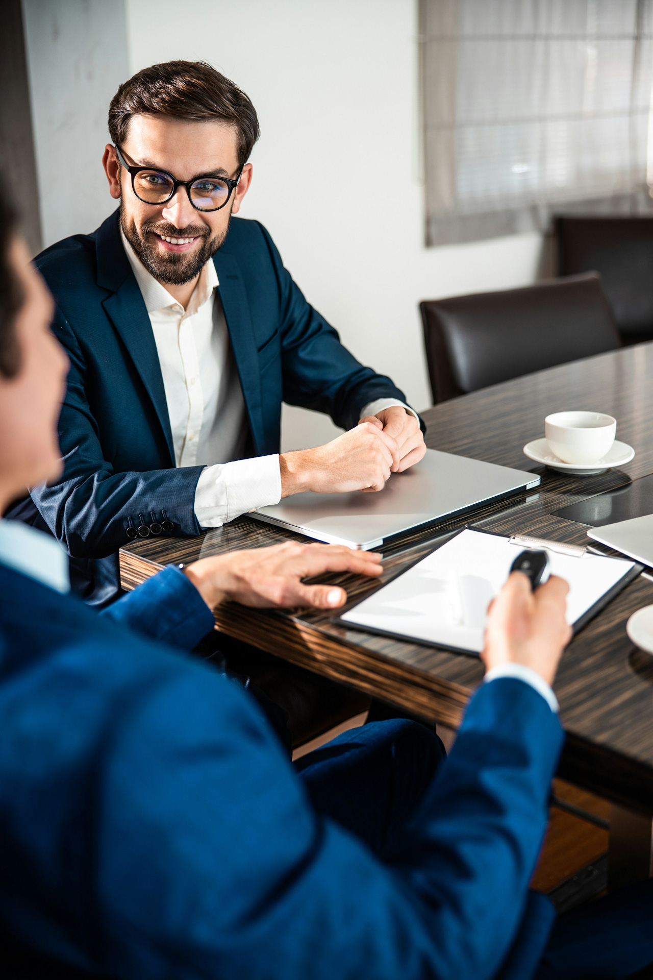 A male healthcare technology consultant is in a meeting with a practice owner in a conference room