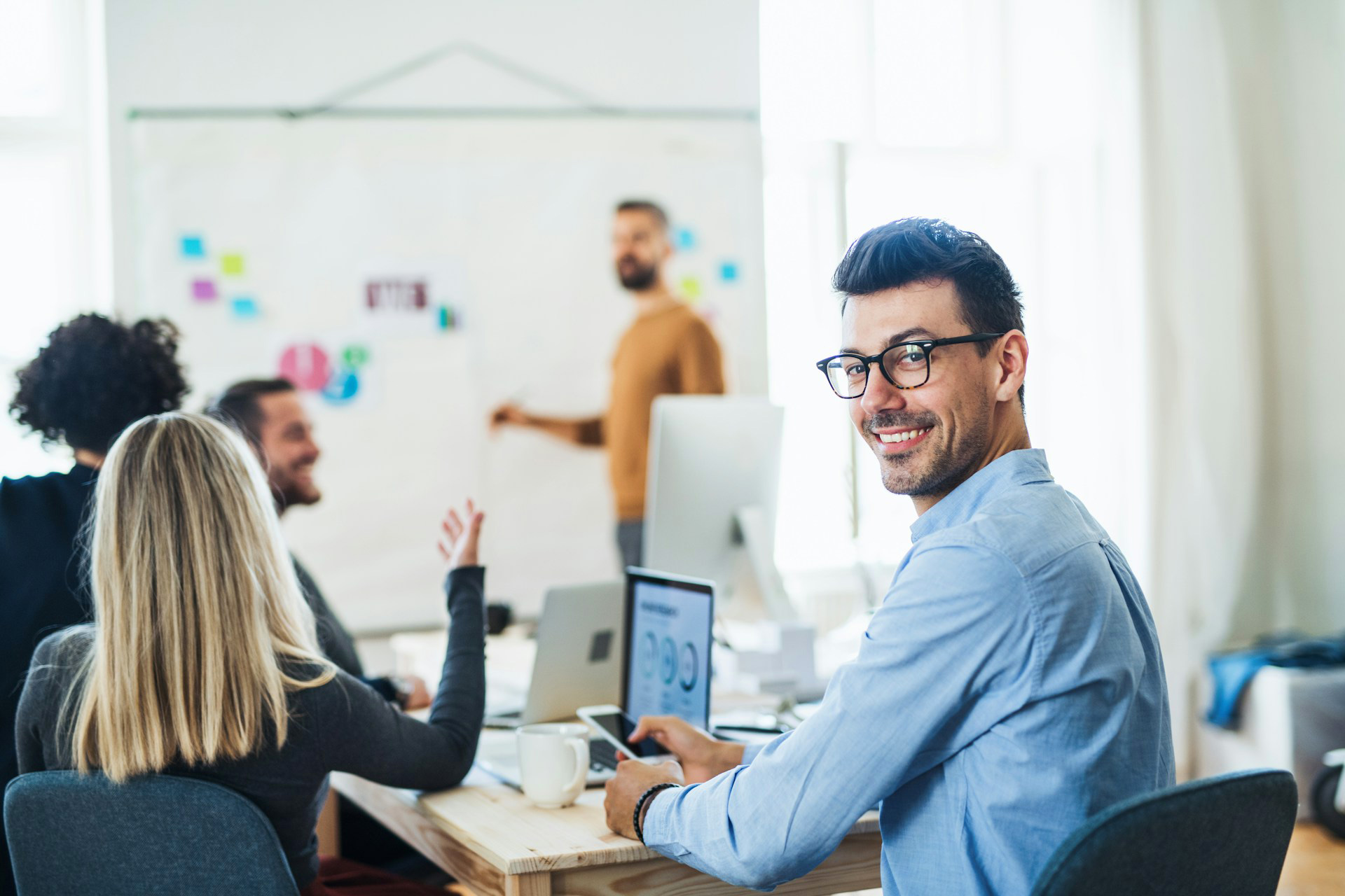 A male healthcare consultant sits in the meeting with his team