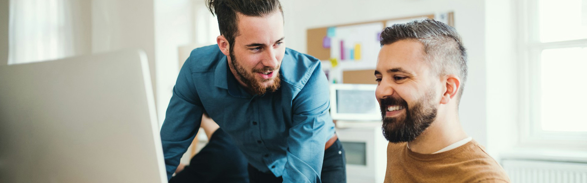 Two white male website design and development consultants are reviewing website design for a healthcare practice